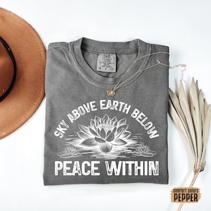 May include: Gray t-shirt with a white graphic that says "Sky Above Earth Below Peace Within". The graphic also features a stylized lotus flower.