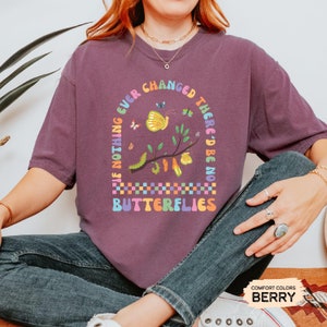 K&ouml;nnte beinhalten: Lilafarbenes T-Shirt mit einer bunten Grafik, auf der steht: "Wenn sich nichts jemals &auml;ndern w&uuml;rde, g&auml;be es keine Schmetterlinge".