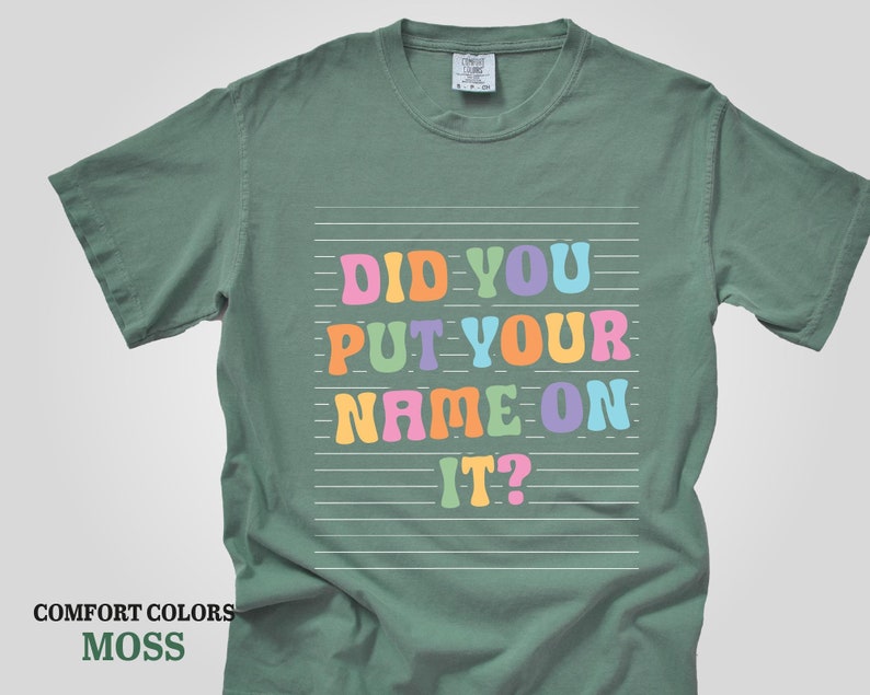 May include: A green t-shirt with the text "Did you put your name on it?" in colorful letters on a white background.