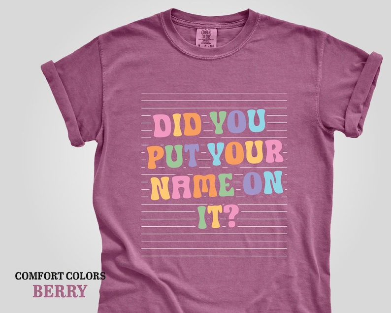 May include: A berry colored t-shirt with the text "Did you put your name on it?" in rainbow colors on a white background.