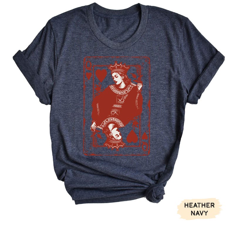 May include: A heather navy blue t-shirt with a red graphic of the Queen of Hearts playing card. The graphic features a stylized illustration of the Queen holding a playing card.
