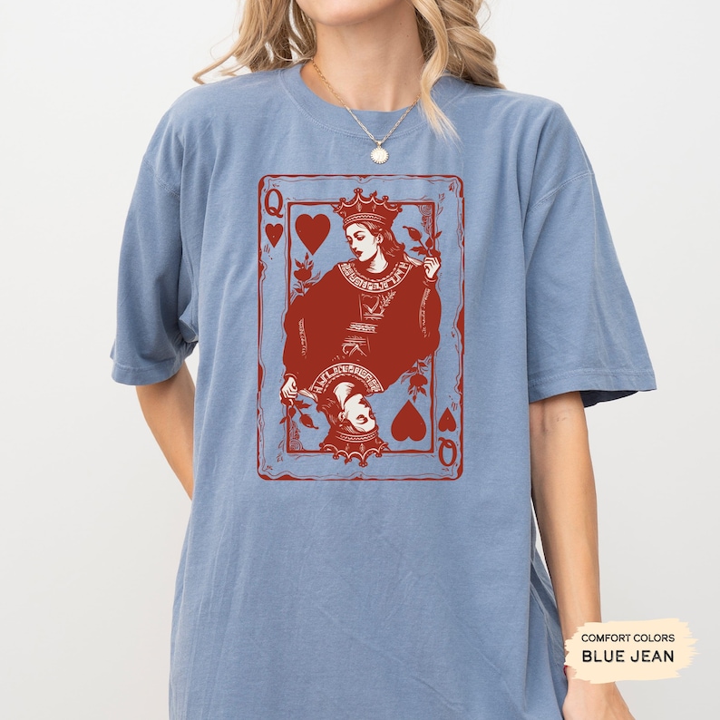 May include: A blue jean t-shirt with a red graphic of the Queen of Hearts playing card. The Queen is depicted with a crown and holding a rose.