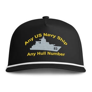 May include: A black baseball cap with a white cord trim along the brim. The front features an embroidered light grey silhouette of a naval ship with the number 83, surrounded by yellow text reading Any US Navy Ship and Any Hull Number.