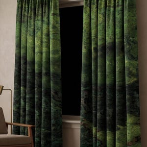 Puede incluir: Dos cortinas de piso a techo que cuelgan de una barra de metal oscuro con anillos. La tela presenta un patrón jaspeado en verde oscuro y negro con texturas arremolinadas. Las cortinas están plisadas en la parte superior y caen en pliegues.