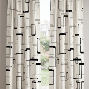 May include: Cream-colored window curtains with a repeating geometric pattern of black and gray rectangles. The curtains are hanging on a silver rod, and a window is visible between the panels.