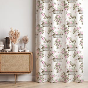 Puede incluir: Cortina floral color crema con un patrón repetido de rosas rosas y follaje verde en jardineras de metal. La cortina tiene una estética vintage y cottagecore, agregando un toque de elegancia. La palabra "FLOWER" está impresa en las jardineras.