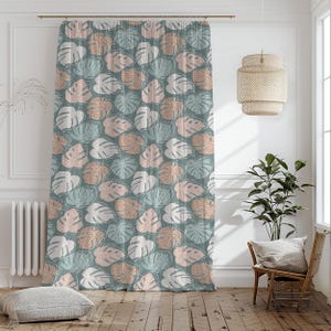 May include: A decorative curtain featuring a repeating pattern of stylized monstera leaves in shades of white, peach, and teal on a muted green background. The curtain hangs in front of a window, adding a touch of nature-inspired design to the room.