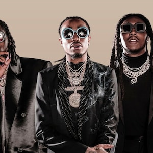 Puede incluir: Tres hombres con trajes negros y gafas de sol. Todos llevan cadenas y colgantes de oro. El hombre del medio lleva un jersey de cuello alto negro.