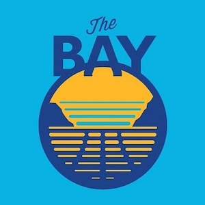 May include: A blue and yellow logo with the text "The BAY" in a stylized font. The logo features a stylized sunset over a body of water.