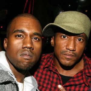 Puede incluir: Dos hombres, uno con una chaqueta gris y el otro con una camisa a cuadros rojos y negros, posan para una foto. El hombre con la camisa a cuadros lleva una gorra de béisbol verde.