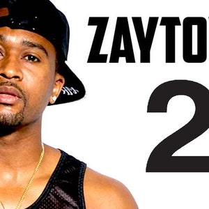 Op de afbeelding: Een man draagt een zwart tanktop, een zwarte baseballpet en een gouden ketting. De tekst "ZAYTOVEN 2" staat op de achtergrond.