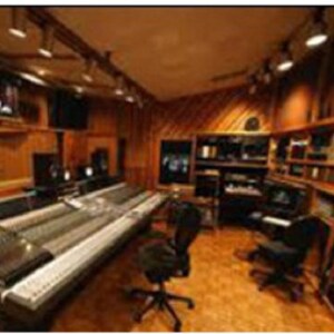 May include: A music production studio with a variety of equipment, including a drum machine, a mixing console, and a computer. The studio is decorated with logos of popular music software companies, including Akai, Roland, Pro Tools, Ableton, FL Studio, and Steinberg.
