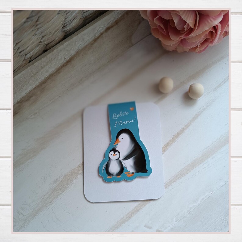 Magnetisches Lesezeichen „Pinguin Piet & Mama“
Diese Bookmarks mit Piet Pinguin und seiner Mama sind  ganz besondere Lesezeichen, die eine leise Botschaft zwischen deine Seiten tragen.

Das Lesezeichen - magnetisch, wurde mit eigener Illustration gestaltet und in liebevoller Herstellung gefertigt. Als besonderes Magnet Lesezeichen hält es deine Seiten sicher zusammen, als Geschenk Mama Geburtstag, 
eine besondere Muttertagsgeschenk Idee oder ein liebevolles kleines Zeichen für zwischendurch.