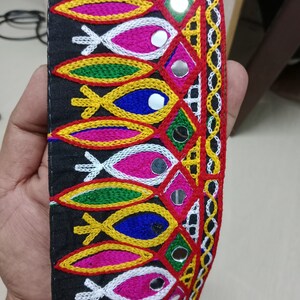 May include: Black fabric trim with colorful embroidered fish shapes and silver mirror accents.