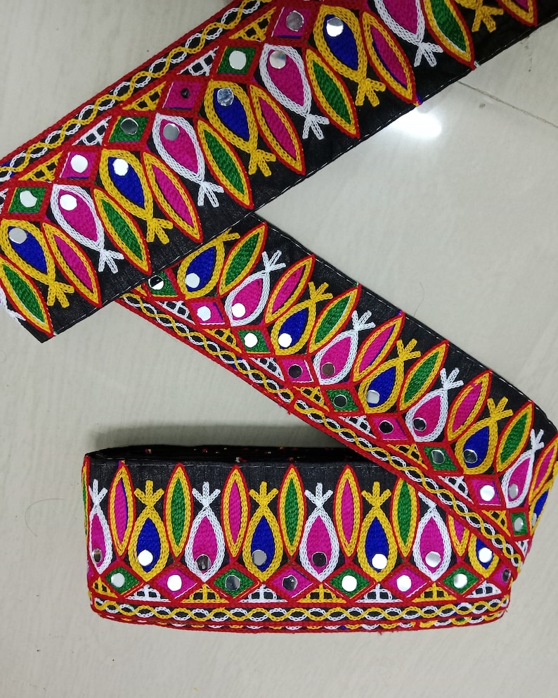 May include: Black fabric trim with colorful embroidery and mirrored accents. The trim features a repeating pattern of fish shapes, geometric designs, and small round mirrors.