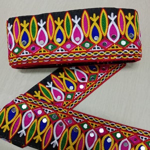 May include: Black fabric trim with colorful embroidery and mirrored accents. The trim features a repeating pattern of stylized leaves and fish shapes.