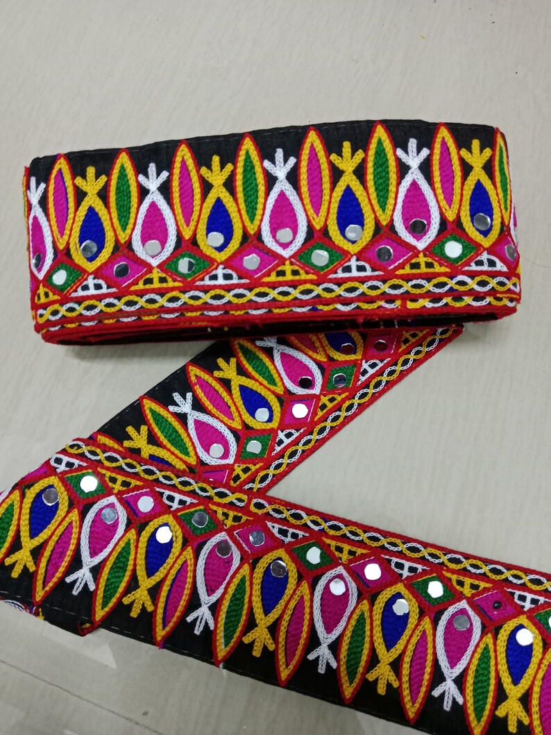 May include: Black fabric trim with colorful embroidery and mirrored accents. The trim features a repeating pattern of stylized leaves and fish shapes.