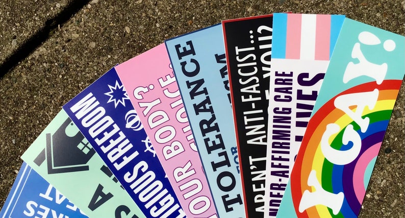 May include: A collection of colorful bumper stickers with messages about tolerance, freedom, and LGBTQ+ rights. The stickers feature phrases like "Our Body, Our Choice", "Aren't Anti-Fascist", "I'm Gay", and "Trans Lives Matter".