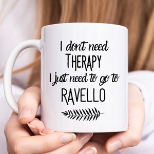May include: White ceramic mug with black text that reads "I don't need therapy I just need to go to Ravello" with a small black leaf design.