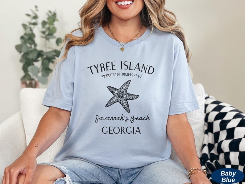 May include: A light blue t-shirt with a black graphic design featuring a starfish and the text "Tybee Island 32.0002&deg; N 80.8457&deg; W Savannah's Beach GEORGIA".