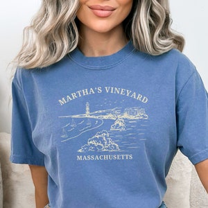 May include: A blue t-shirt with a white graphic design of a lighthouse and the text "Martha's Vineyard, Massachusetts".