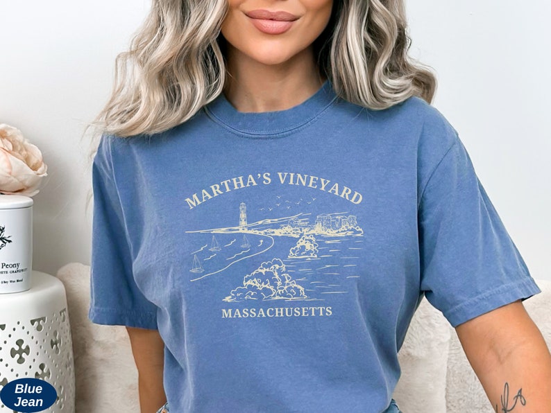 May include: A blue t-shirt with a white graphic design of a lighthouse and the text "Martha's Vineyard, Massachusetts".