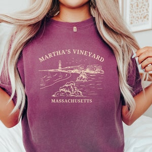 May include: A purple t-shirt with a graphic design of a lighthouse, beach, and the text "Martha's Vineyard, Massachusetts".