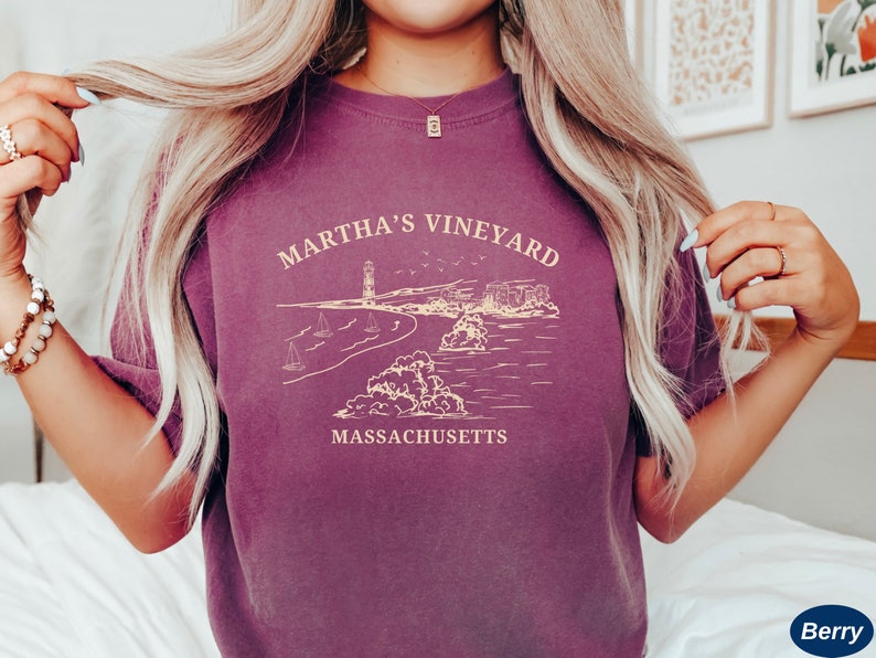 May include: A purple t-shirt with a graphic design of a lighthouse, beach, and the text "Martha's Vineyard, Massachusetts".