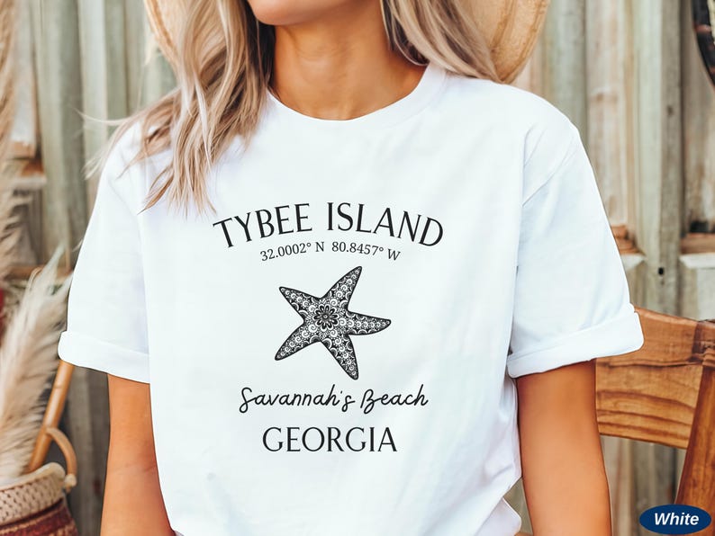 May include: White t-shirt with black text that reads "Tybee Island 32.0002&deg; N 80.8457&deg; W Savannah's Beach GEORGIA" and a black and white starfish graphic.