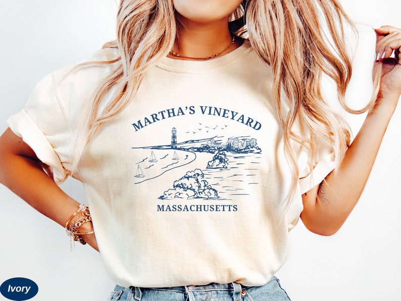 May include: A white t-shirt with a blue graphic design that says "Martha's Vineyard, Massachusetts". The graphic features a lighthouse, sailboats, and a coastline.