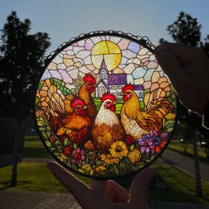 May include: A stained glass window depicting a rural scene with four chickens and a church in the background. The chickens are brown, yellow, and red with detailed features. The church is white with a purple roof and a tall steeple. The background is a colorful mosaic of glass.
