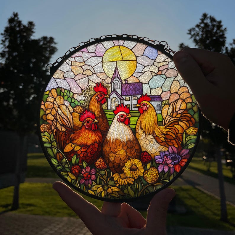 May include: A stained glass window depicting a rural scene with four chickens and a church in the background. The chickens are brown, yellow, and red with detailed features. The church is white with a purple roof and a tall steeple. The background is a colorful mosaic of glass.