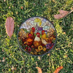 May include: A stained glass round wall decor featuring four colorful roosters and a church in the background. The roosters are surrounded by flowers and greenery.
