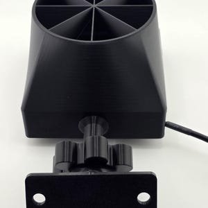 May include: A black, 3D-printed object with a cylindrical top divided into eight sections. It has a conical base and a mounting bracket with two holes. A small, adjustable knob and a power cord are also visible.