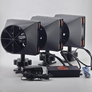 May include: Three black, angular devices with fan blades and copper-colored accents. Each device is mounted on a black base and connected by black wires. An adapter and a control box with a red logo are also present.