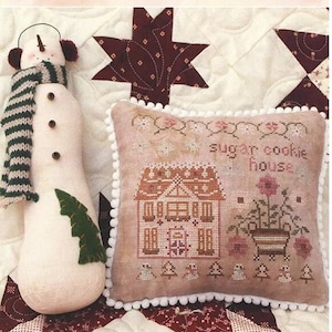May include: Cross stitch pattern for a sugar cookie house with a pink flower pot and the text "sugar cookie house". The pattern is part of the "Houses on Peppermint Lane" series, chart 3 of 9, designed by Lori Pengelly.