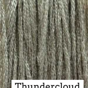 May include: Close-up of a skein of yarn in a light gray color with a subtle brown undertone. The yarn is labeled "Thundercloud".