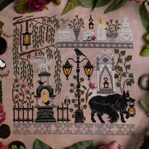 Może przedstawiać: Wzór do haftu krzyżykowego przedstawiający straszną scenę cmentarza z czarnym kotem, latarniami i płaczącym wierzbą. Wzór jest wyszyty na jasnobrązowej tkaninie.