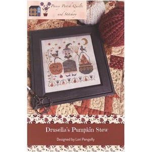 Puede incluir: Arte de punto de cruz enmarcado con temática de Halloween. La obra de arte representa una bruja, un gato y una calabaza. El marco es negro. El texto "Drusella's Pumpkin Stew" está en la parte inferior, diseñado por Lori Pengelly.
