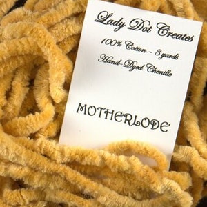 May include: A skein of 3 yards of hand-dyed, 100% cotton chenille yarn in a golden yellow color. The yarn is labeled "Motherlode" by Lady Dot Creates.