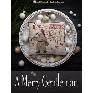 May include: A cushion with a cross-stitch design of a figure in winter attire, playing a musical instrument. The cushion is on a white tray with decorative balls and ornaments. The word "MERRY" is on the cushion. The text "A Merry Gentleman" is at the bottom.