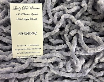 May include: A close-up of a pile of soft, hand-dyed chenille yarn in a light blue color. The yarn is 100% cotton and is 3 yards long. The label reads "Lady Dot Creates" and "Anemone".