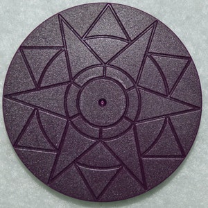 May include: A dark purple circular turntable with a starburst design and a central hole. The turntable has a textured surface.