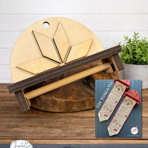 May include: A wooden tomato cage with a round base and a geometric design. The cage has a dark brown frame and a wooden dowel. A small blue card with the text "OH TOMATO" is visible.
