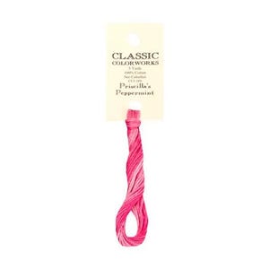 Peut inclure: Un écheveau de fil à broder Classic Colorworks en Priscilla's Peppermint. Le fil est une mèche torsadée de fils roses et blancs, avec une étiquette en papier en haut. L'étiquette indique "CLASSIC COLORWORKS" et "Priscilla's Peppermint".