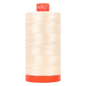 May include: A spool of Aurifil thread in a cream color. The spool is orange with the Aurifil logo in pink.