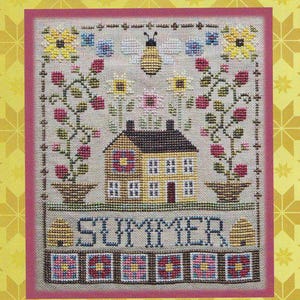 Peut inclure: Un modèle de point de croix intitulé Summer Saltbox #238 représentant une maison jaune, une abeille, des fleurs en pot et le mot SUMMER. Le motif inclut une bordure de carrés style patchwork sur un fond en tissu clair avec un cadre rose.