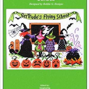 Op de afbeelding: Borduurpatroon voor een Halloween-thema scène met een vliegende school genaamd "Gertrude's Flying School". De scène bevat heksen, een klaslokaal, een ketel en pompoenen. Het patroon is ontworpen door Bobbie G. Designs en is verkrijgbaar bij Imaginating.