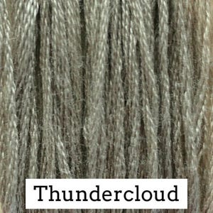 Könnte beinhalten: Nahaufnahme einer Garnspule in der Farbe Thundercloud. Das Garn ist eine Mischung aus Grau und Beige mit einem strukturierten Aussehen. Der Text "Thundercloud" wird in einem weißen Rechteck am unteren Rand des Bildes angezeigt. Ideal für Strick- und Häkelprojekte.