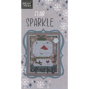 May include: A cross stitch pattern featuring a snowman with a red nose and a green hat. The pattern is titled "Flair Sparkle" and is from Bent Creek.